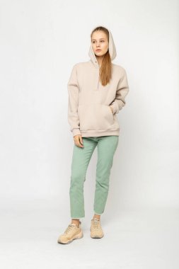 Yeşil kargo pantolonlu ve bej kapüşonlu kız beyaz üzerinde izole edilmiş.