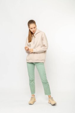 Yeşil kargo pantolonlu ve bej kapüşonlu kız beyaz üzerinde izole edilmiş.