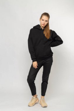 Siyah kargo pantolonlu ve siyah kapüşonlu bir kız.