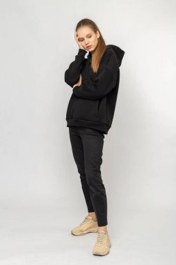 Siyah kargo pantolonlu ve siyah kapüşonlu bir kız.