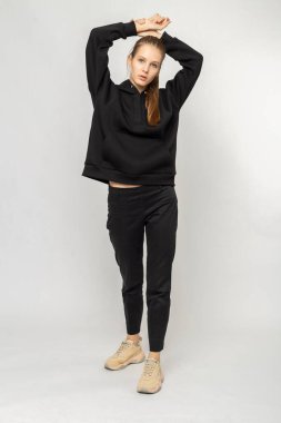 Siyah kargo pantolonlu ve siyah kapüşonlu bir kız.