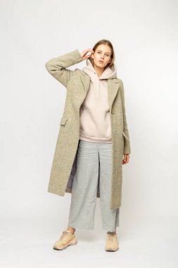 Beyaz arka planda izole edilmiş bej ceketli bir kız.