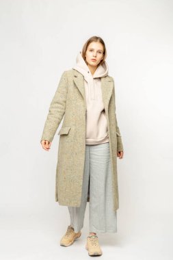 Beyaz arka planda izole edilmiş bej ceketli bir kız.