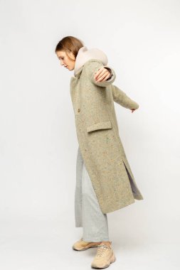 Beyaz arka planda izole edilmiş bej ceketli bir kız.