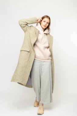 Beyaz arka planda izole edilmiş bej ceketli bir kız.