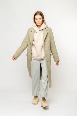 Beyaz arka planda izole edilmiş bej ceketli bir kız.