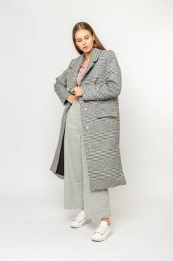 Beyaz arka planda izole edilmiş gri ceketli bir kız.