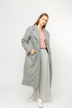 Beyaz arka planda izole edilmiş gri ceketli bir kız.