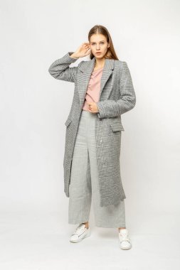 Beyaz arka planda izole edilmiş gri ceketli bir kız.