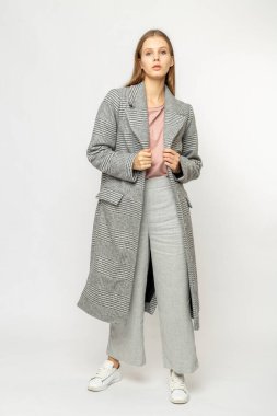 Beyaz arka planda izole edilmiş gri ceketli bir kız.