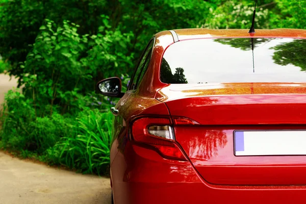 Back window of red car parked on the street in summer sunny day, rear view. Mock-up for sticker or decals