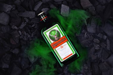 Ukraine, Poltava - July 11, 2022: Bottle of Jagermeister, German digestif made with 56 herbs and spices. Bottle in coals.