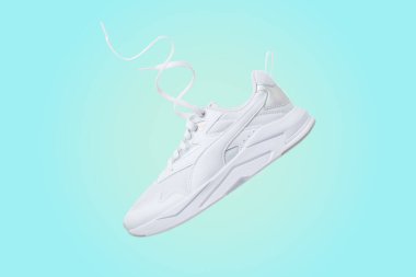 POLTAVA, UKRAINE - July 25, 2022: Puma white sneakers. Puma X-Ray Lite Metallic Wmn. White flying sneakers on blue and yellow gradient background
