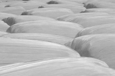 Faded black and white background of plastic wrapped hay bales 