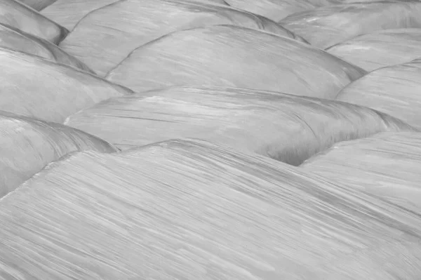 Faded black and white background of plastic wrapped hay bales