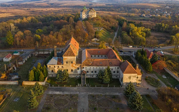 Ukrayna 'nın Olesko kasabasındaki şatonun arka planında, gün batımında Roma Katolik Kilisesi' nin 1737 yılındaki Capuchin Manastırı 'nın hava manzarası.
