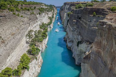 Parlak güneşli bir günde beyaz bulutlar ile mavi gökyüzü karşı Korint kanalı güzel sahne. Beyaz gemi turkuaz suda yüzen kayaların arasında