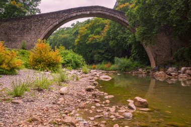 Portaikos Köprüsü, Yunanistan 'ın Thessaly kentindeki Trikala ilinin Portaikos Nehri üzerinde 1514 yılında inşa edilen tek bir kemerli taş köprü. Yazın manzara manzarası.