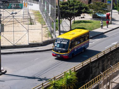 Medellin, Antioquia, Kolombiya - 23 Aralık 2020: Birçok ağaç yakınındaki Paved Yolu 'nda Kolombiya Bayrağı Seyahatleri Renkleri ile Boyanmış Otobüs