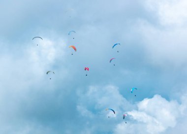 Çeşitli Renklerin Birçok Paraglider Bulutlarla dolu Mavi Arkaplanda Uçuyor