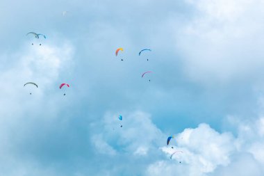 Çeşitli Renklerin Birçok Paraglider Bulutlarla dolu Mavi Arkaplanda Uçuyor