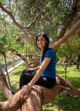 Peruvian Woman Sitting on a Tree Branch, Surrounded by Nature