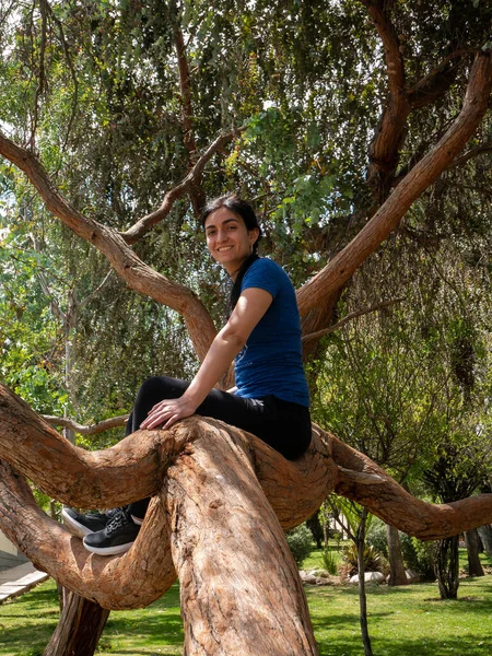Peruvian Woman Sitting on a Tree Branch, Surrounded by Nature