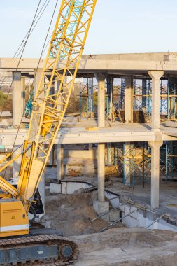 Göl kıyısında mavi gökyüzüne karşı yapım aşamasında olan vinç ve bina