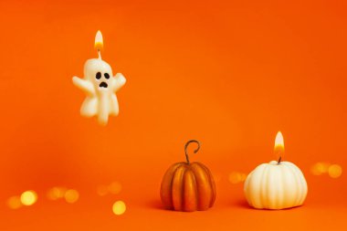 Hayalet şeklinde mumlar yakmak ve turuncu arka planda balkabağı. Cadılar Bayramı, Şükran Günü, hasat festivali konsepti