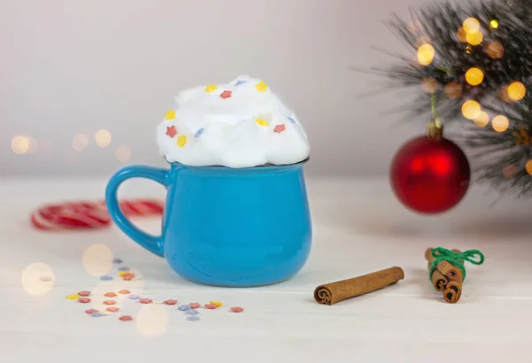 クリスマスツリーの近くのブルーカップにホイップクリームと星型の装飾が施された美しいお祝いのドリンク — ストック写真