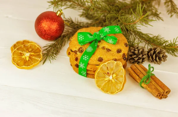 木のテーブルの上のトウヒの枝の近くでクリスマスクッキーとシナモンとレモンのウェッジ 休日のペストリーとデザート — ストック写真