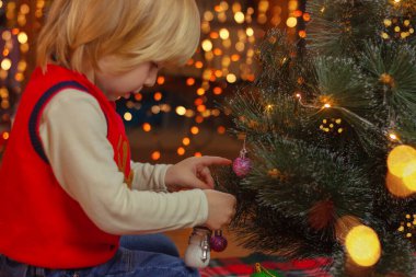 Sarışın küçük çocuk Noel ağacını süslüyor. Noel ve yeni yıl, geliş, çocukluk, tatil konsepti