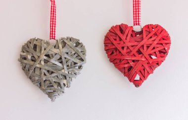 Gri ve kırmızı hasır kalpler açık arkaplanda bir kurdeleye asılı. Aşk, sevgililer günü ve romantizm kavramı..