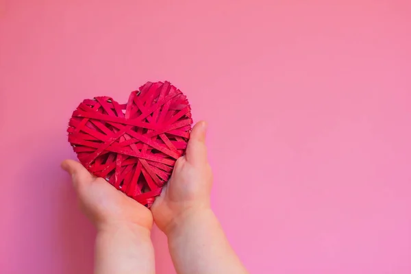 Руки Ребенка Держат Красное Плетеное Сердце Розовом Фоне Копировальным Пространством — стоковое фото