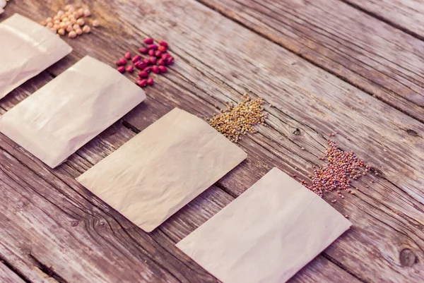Kırsal ahşap bir masa üzerinde kağıt paketler içinde tarım tohumları, seçici bir odaklanma. Çiftçilik, bahçıvanlık, organik doğal ürünler ekme kavramı.