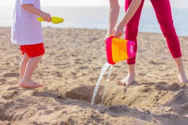 Çocuklar sahilde oyuncaklarla oynarken eğleniyor. Ekin fotoğrafı, yüzü yok. Kardeş kavramı, çocukluk, yaz tatili ve aktiviteler