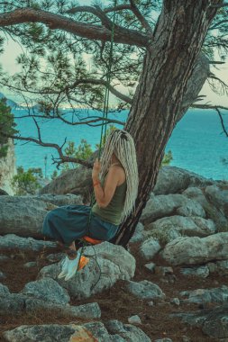 Rasta saçlı kız Akdeniz kıyısında bir salıncakta dinleniyor.. 