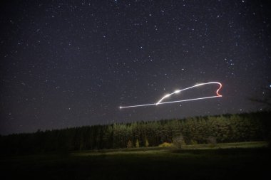 Yıldızlı gökyüzünde gece bir kuadkopter uçurmak. 