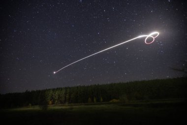 Yıldızlı gökyüzünde gece bir kuadkopter uçurmak. 