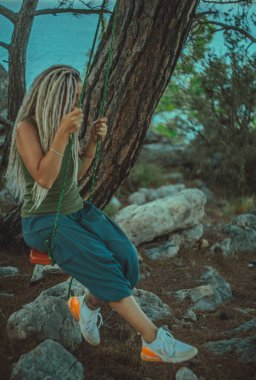 Rasta saçlı kız Akdeniz kıyısında bir salıncakta dinleniyor.. 