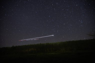 Yıldızlı gökyüzünde gece bir kuadkopter uçurmak. 
