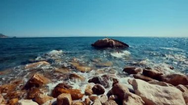 Akdeniz kıyısındaki bir kayanın üzerinde bir kuş oturuyor.