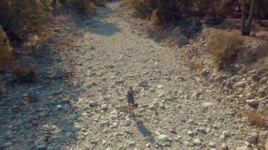 Adam kurumuş bir nehrin yatağında yürüyor.