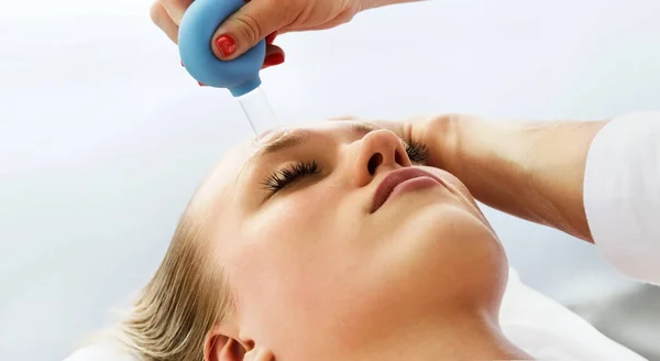 Güzellik uzmanı kozmetik uzmanı, kupa ile yüz temizleme masajı yapıyor. Müşteri için bir güzellik kliniğinde profesyonel kozmetik prosedür. Alnındaki kırışıklıkları düzeltiyorum. Kozmetoloji spa konsepti.