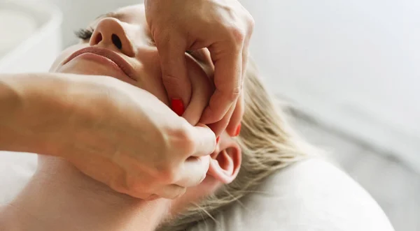 Güzellik uzmanı kozmetik uzmanı yüz masajı, çimdikleme ve yuvarlama tekniği, profesyonel kozmetik prosedürünü müşteriler için bir güzellik kliniğinde yapıyor. Cilt bakımı ve kozmetoloji spa konsepti.