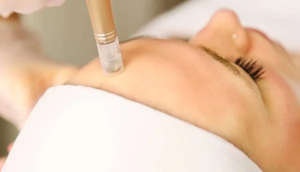 Güzellik uzmanı kozmetik uzmanı Dermapen ile kısmi mikronedle mezoterapi yapıyor. Klinikte müşteri için hırdavat kozmetolojisi. Bulanık seçici odak.