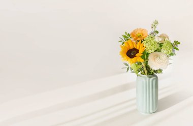 Masadaki vazoda çiçekli buket beyaz bir duvarın arkasında. Kopya alanı ile minimal İskandinav modeli.