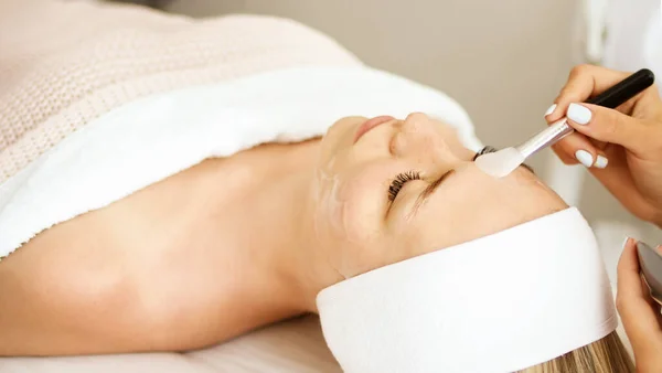 Güzellik uzmanı kozmetik ürün jel soyma maskesini spatulayla, profesyonel bir klinikte müşteriler için kullanıyormuş. Cilt bakımı ve kozmetoloji spa konsepti.