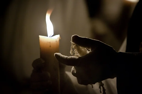 Hand met een katoenen ondersteunt handschoen met gesmolten wax kaars — Stockfoto