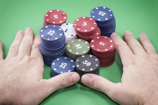 Poker chips en handen boven het op groene tafel — Stockfoto